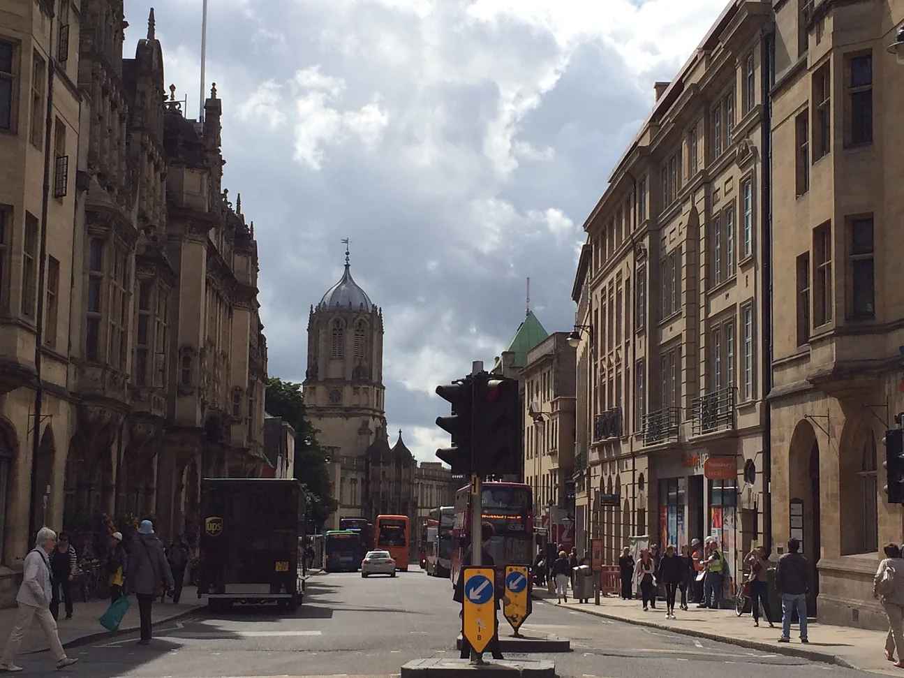View of a road in an old town with medieval towers on the horizon: St Aldate's, a thoroughfare through the city centre, and Christ Church's Tom Tower.