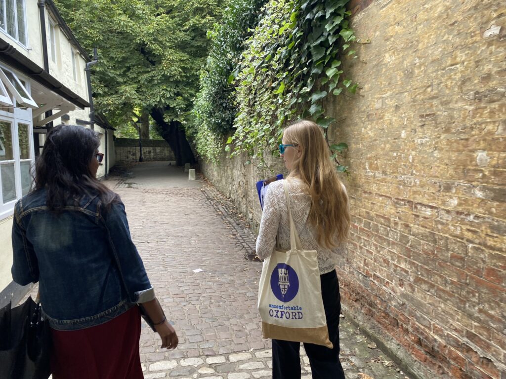An Uncomfortable Oxford guide leads a participant through a narrow stone sidestreet.
