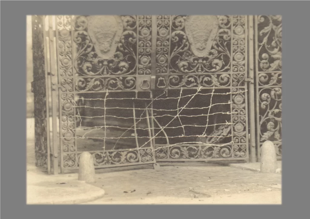 Black and white archive photograph of a damaged iron gate, following 1921 protests. 