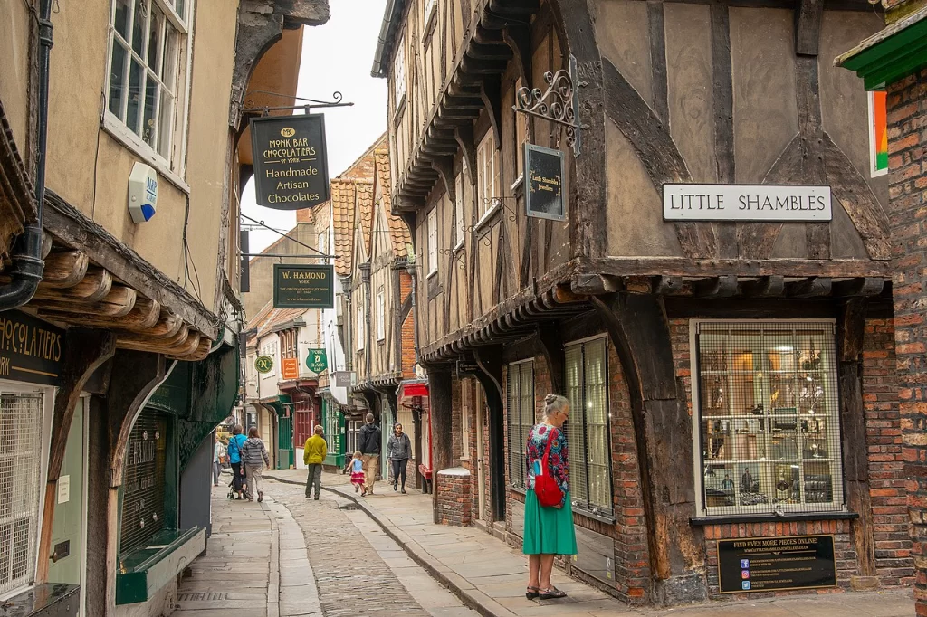 Picture of a medieval looking street today with shops and pedestrians.