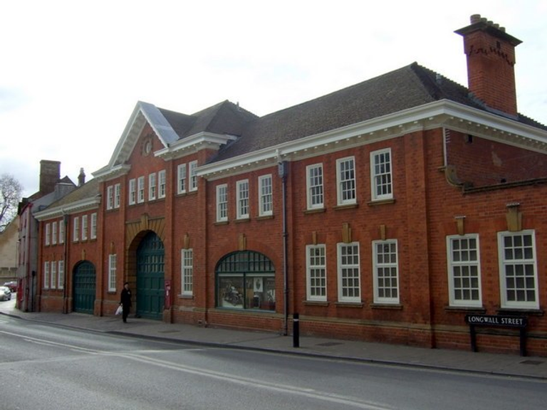 Red brick building with large garage door along a street. 