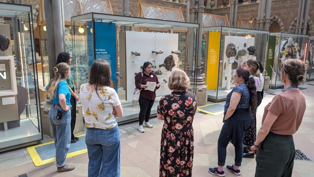 A group of people stand around a tour guide on a tour of the Museum of Natural History in Oxford