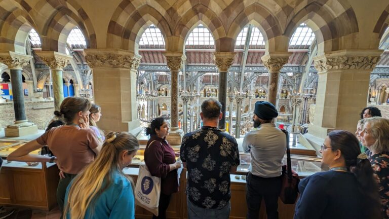 A group of people stand around a tour guide on a tour of the Museum of Natural History in Oxford